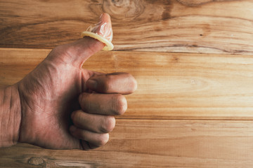 Condoms in the hands of men who made gestures with a wooden background.