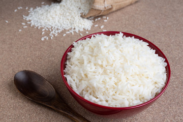 Cooked rice in a red cup placed on the plywood floor.