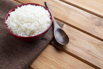 Cooked rice in a red cup placed on the plywood floor.