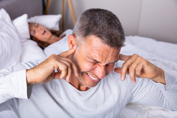 Fototapeta na wymiar An Angry Man With Snoring Wife On Bed