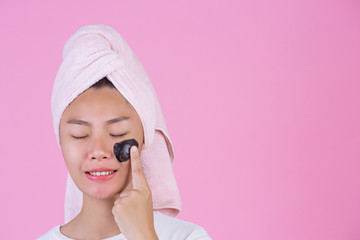 Beauty cosmetic peeling. Young female with black peel off mask on skin cosmetic skin care peeling product on face on a pink background.