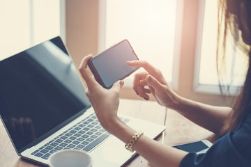 Obraz premium Woman using smart phone while working in the coffeeshop. Modern and smart lifestyle with online mobile technology.