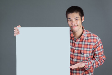 A short-haired man wearing a red plaid shirt stands with a white label on a gray background.