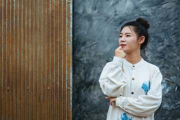 The woman wearing glasses stands to show that the background is gray cement and rust red.