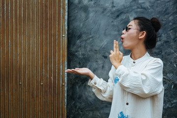 The woman wearing glasses stands to show that the background is gray cement and rust red.