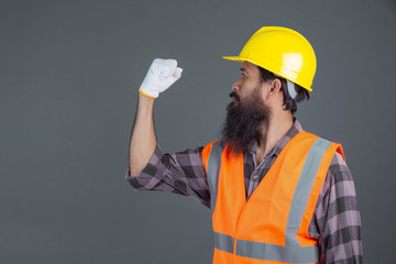 An engineering man wearing a yellow helmet wearing white gloves showed a gesture on a gray background.