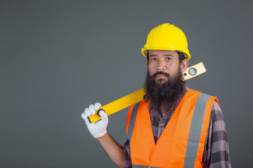 An engineering man wearing a yellow helmet holding a water level meter on a gray background.