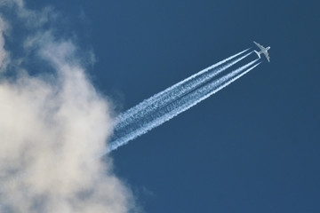 Airplane In Blue Sky With Plane Trails