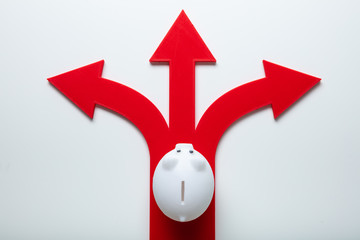 White Piggybank Over Red Arrow Signs Showing Various Direction