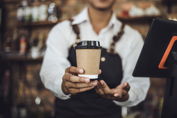 Male Barista preparing coffee for customer in coffee shop. Cafe owner serving a client at the coffee shop.