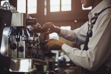 Male Barista preparing coffee for customer in coffee shop. Cafe owner serving a client at the coffee shop.