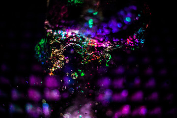 Colored texture of water in the rays of LED light. Water splashes highlighted from below. Fountain in the dark.