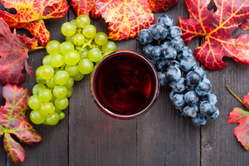 glass of red wine and grapes on black wooden table background