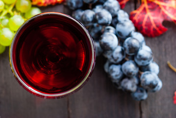 glass of red wine and grapes on black wooden table background
