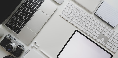 Top view of modern workplace with laptop computer, camera, tablet, office supplies on white desk background