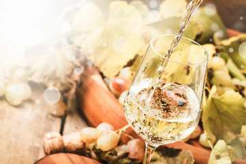White wine being poured into a glass, vintage wood background, selective focus - obrazy, fototapety, plakaty
