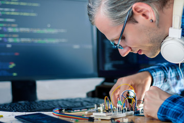 Developer is connecting breadboard to microcontroller for creating prototype of electronic device....