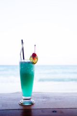 Blue hawaii cocktail on table beach background.