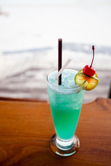 Blue hawaii cocktail on table beach background.