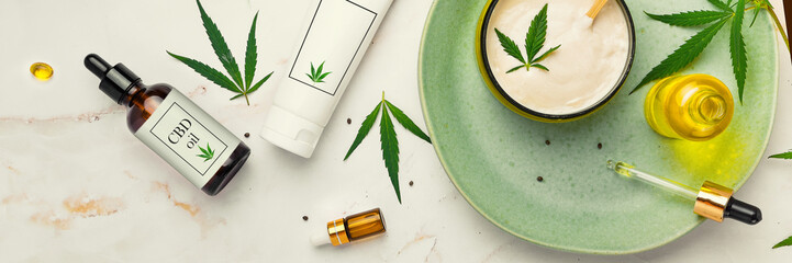 Cosmetics with cannabis oil on a turquoise plate on a light marble background. Concept of luxury...