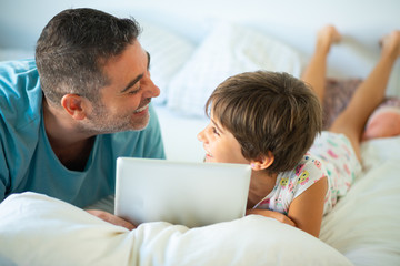 Obraz premium Middle-age father with her eight years daughter using digital tablet in bedroom.