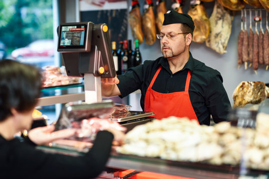 Butcher Attending A Customer In A Butcher's Shop