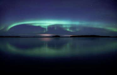 Northern lights dancing over calm lake in Farnebofjarden national park in Sweden.