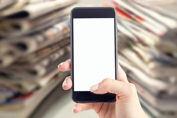 Hand holding a smartphone with a blank screen. Newspapers blurred in the background. Concept of the morning press and telephone in hands.