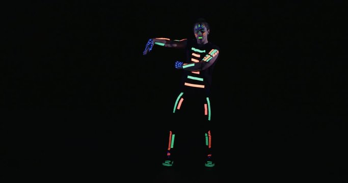 Studio, slow motion, male neon-clad dancer dancing in blacklight, London
