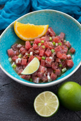 Turquoise bowl with tuna ceviche, vertical shot on a grey stone surface, closeup