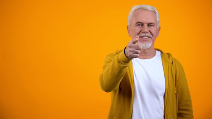 Confident modern senior man pointing finger on camera, welcoming to nursing home