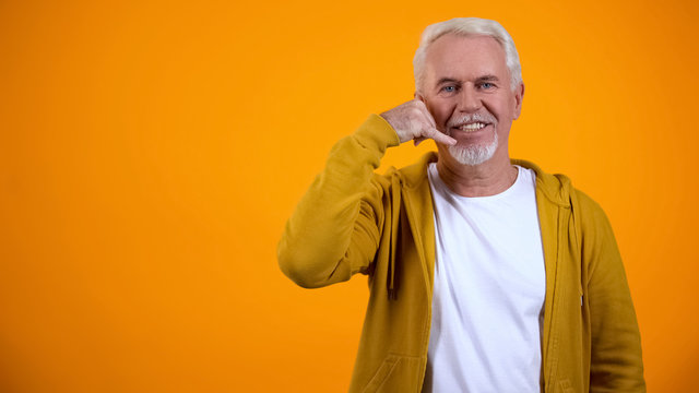 Retired male showing call me gesture, flirting on camera, communication concept