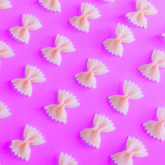 Pattern of raw pasta bow on pink background. Italian food.