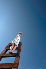 Cute little boy is trying to paint the sky with tassel , climbing up the stairs to very high