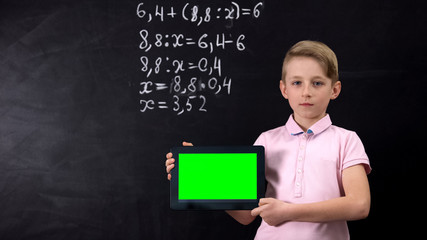 Schoolboy holding tablet with green screen, application for learning math