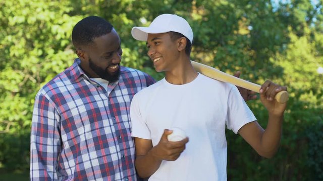 Dad encouraging son holding baseball bat, sport leisure, family connection hobby