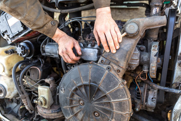 Unrecognizable man repairs the engine of an old car