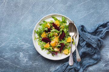 Beets, orange, pine nut, olive oil, feta cheese and arugula salad in ceramic plate on old concrete...