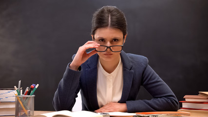 Angry teacher looking aggressively to camera taking off glasses, strict lecturer