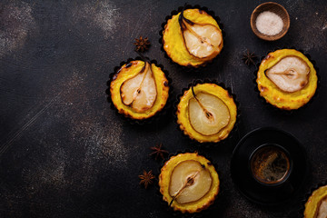Pears and custard mini tarts on a dark brown concrete old table background. Top view.