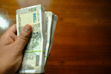 hand with 500 rupee money isolated on wood  background