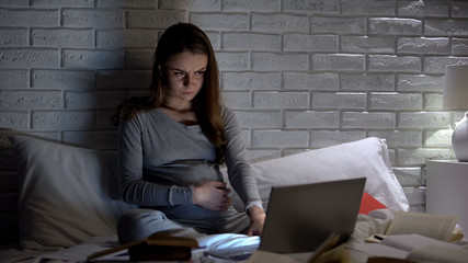Pregnant girl reading books and websites, worrying about baby health, belly pain