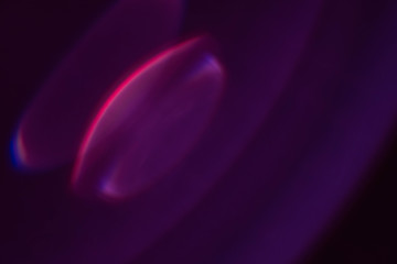 Defocused glow. Dark purple abstract art background. Colored lens flare. Blur round flash light.