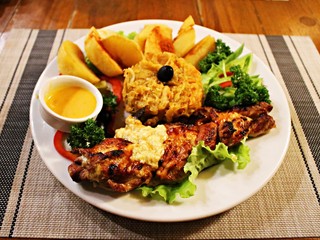 Grilled piece of pork, stewed cabbage, fried potatoes and fresh vegetable salad