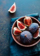 Macro photo of ripe figs in a wooden small bowl on a table.