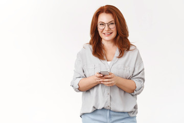Charming cheerful redhead middle-aged mother always stays touch children texting via social media...