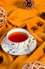 Hello Autumn background. Bright yellow wool sweater, cup of tea, natural decorative grapevine balls, star anise and pine cones. Autumn coziness concept