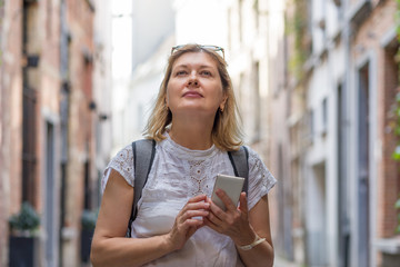 An adult woman enjoys the sights while traveling through a European city. An elderly woman is...