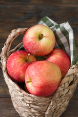Red apples in a basket on a wooden table. Rustic style