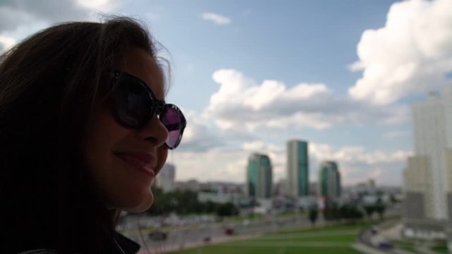 pretty lady silhouette makes selfie on smartphone standing on balcony against modern city buildings closeup slow motion